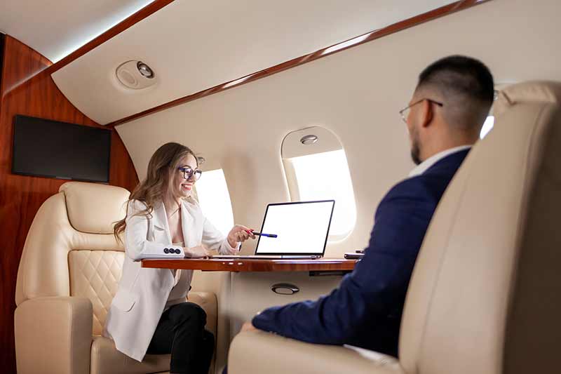 Man and woman sitting across from each other on private jet review their invoice and are pleased with the private jet pricing 
